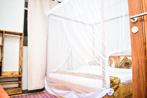 a bedroom with a bed with a mosquito net at Uhuru House And Restaurant in Nungwi