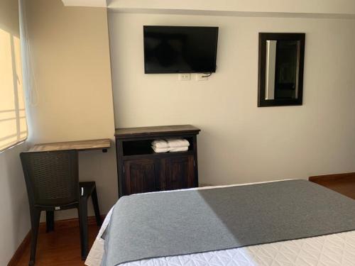 a bedroom with a bed and a chair and a television at Hotel Santa Elena Norte in Tunja