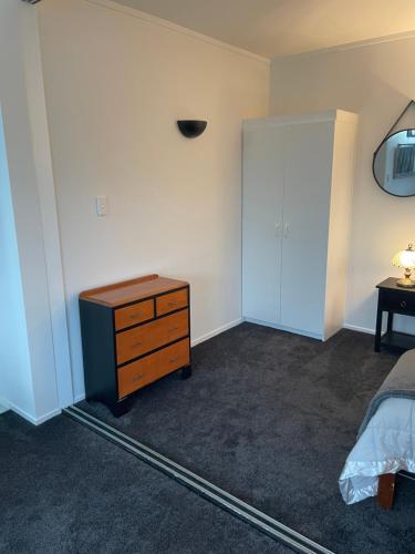 a bedroom with a bed and a dresser and a door at Ohope Beach Dreamer in Ohope Beach