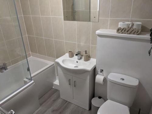 Baño blanco con aseo y lavamanos en 4 Bedroom Home Near York Racecourse, en York
