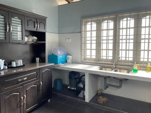 a kitchen with wooden cabinets and a sink and windows at Hj Hassan Guest House Bungalow B in Kuala Terengganu