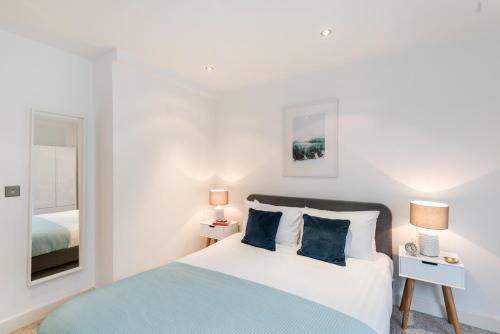 a white bedroom with a bed and a mirror at Farringdon Apartments in London