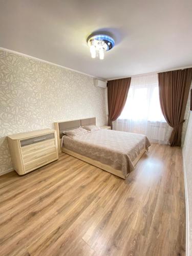 Schlafzimmer mit einem Bett und Holzboden in der Unterkunft Уютные апартаменты в центре города in Oral