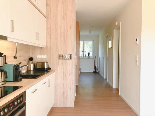 a kitchen with white cabinets and a wooden floor at PerlePlau in Plau am See