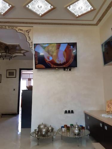 a living room with two tables and a tv on the wall at Appartement Haut Standing Petit Déjeuner INCLUS in Tangier