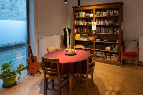 a dining room table with a bowl of fruit and a guitar at Bed en boek in Oudenaarde