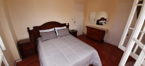 1 dormitorio con cama blanca y espejo en EN EL CORAZON DE LA FELIZ Excelente departamento con estacionamiento gratuito privado y vista al mar!! 3 AMBIENTES en Mar del Plata