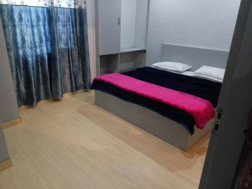 a bedroom with a bed with a pink blanket on it at Hotel Shubham in Jalandhar