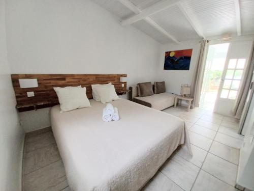 a bedroom with a large white bed and a couch at La Rose du Bresil Marie-Galante in Capesterre