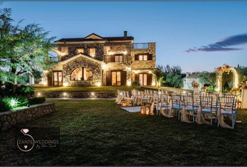 a wedding ceremony in front of a large house with chairs at Palazzo Di P Villa, World 5th Award in Kalpaki