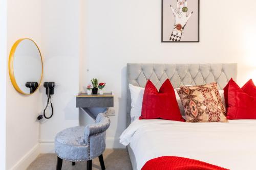 Un dormitorio con una cama con almohadas rojas y una silla en LUXURY 2 Bedrooms - 2 BATHROOMS - F5, en Londres