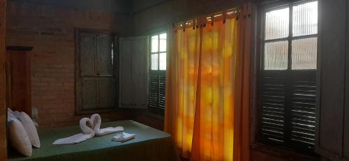 a room with a bed with shoes and a window at Aldea Zen Chales Privativos in Ouro Preto