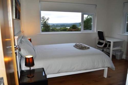 a bedroom with a white bed and a desk and a window at Twin Lake View - Bungalow in Pontoon in Foxford