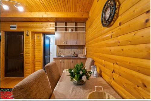 a dining room with a table and a clock on a wooden wall at Zlatibor Brvnare Zakos in Zlatibor