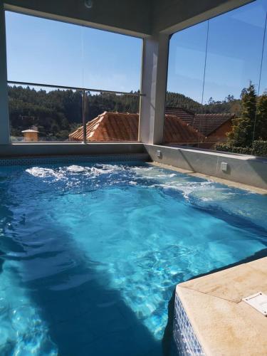 a large swimming pool with blue water and large windows at Pousada Winterhaus in Monte Verde