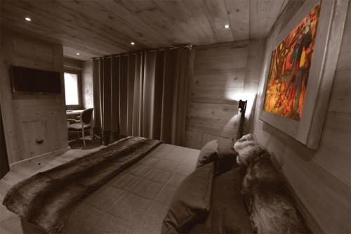 a bedroom with a large bed and a television at La Maison de Dolphe Chalet de Charme & Art gallery in Brusson