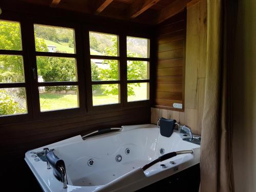 a large bath tub in a room with windows at Casas rurales Valle de Bueida, jacuzzi en el El Palacio y Viscárcel in Bárzana