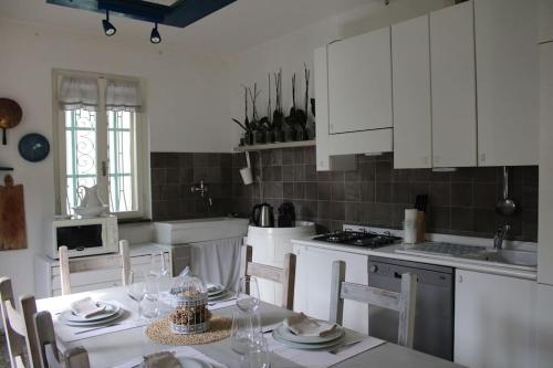 a kitchen with white cabinets and a table with chairs at Casa Sivori sul lago di Garda con ampio giardino in Desenzano del Garda