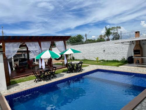 a pool with chairs and umbrellas next to a house at Casa Boto Tucuxi 2 in Novo Airão