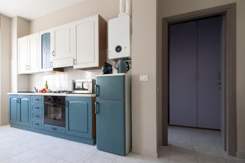 a kitchen with a blue refrigerator and white cabinets at Happy Home in Saronno