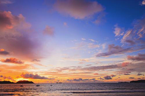 a sunset over the ocean with boats in the water at Bahia del Sol Beach front Boutique Hotel in Potrero