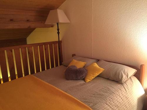 Cette chambre comprend un lit avec deux oreillers et une lampe. dans l'établissement La Foux D’Allos - Studio cosy - pied des pistes, à Allos