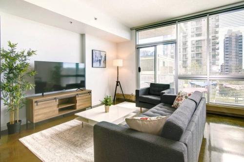 a living room with a couch and a tv at Stylish 1BR, Stampede & Free Parking by Doorbed in Calgary