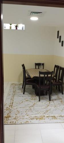 a dining room with a table and chairs on a rug at بناية يا هلا in Ajman 