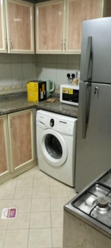 a kitchen with a washing machine and a refrigerator at بناية يا هلا in Ajman 