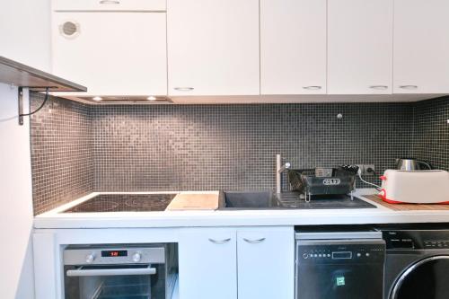 une cuisine avec des armoires blanches et un four à plaques de cuisson dans l'établissement Duplex Design & Moderne en plein cœur de Paris, à Paris