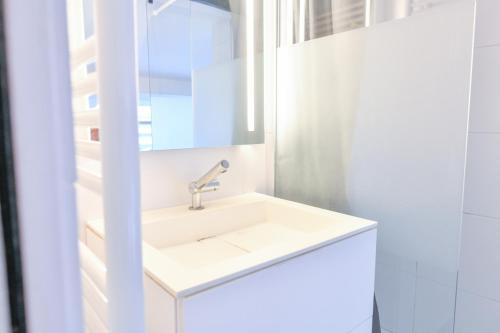 une salle de bain blanche avec un lavabo et un miroir dans l'établissement Duplex Design & Moderne en plein cœur de Paris, à Paris