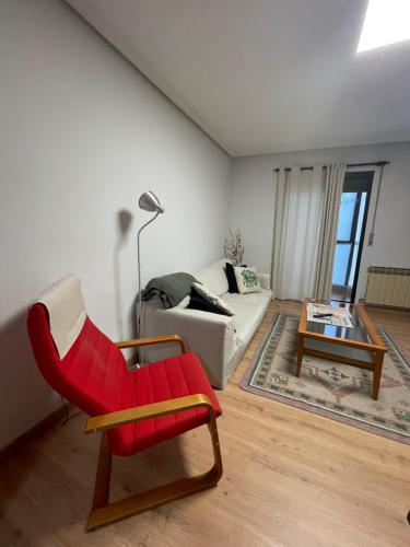 a living room with a red chair and a couch at San Pablo, piso céntrico in Palencia