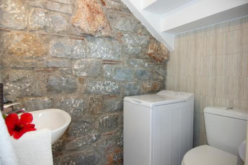 a stone walled bathroom with a toilet and a sink at Mani Cosy View Maisonette in Riglia