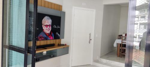 TV en la pared en el baño con espejo en Apartamento Guarujá Astúrias en Guarujá