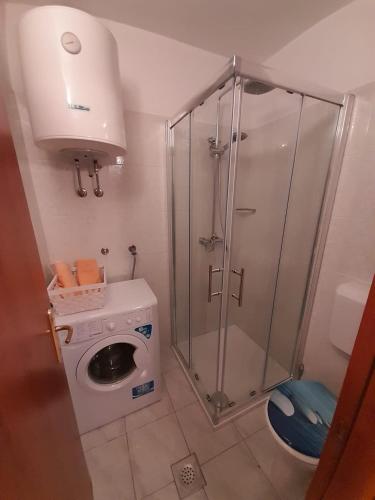 a bathroom with a shower and a washing machine at Apartman Luce in Jadranovo