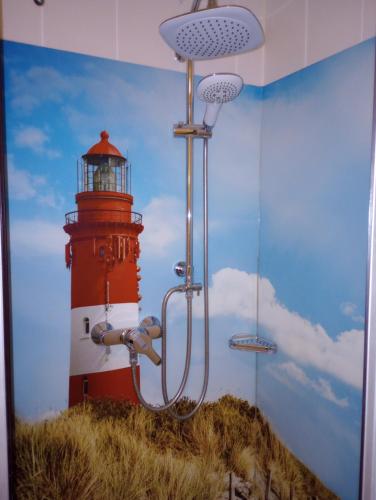 ein Gemälde eines Leuchtturms und eine Dusche in einem Zimmer in der Unterkunft Villa Regina Maris Fewo Lachmöwe 70 m zum Strand in Bansin