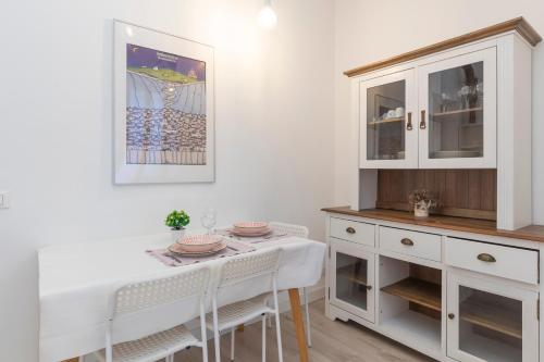 uma sala de jantar com uma mesa e armários brancos em [New flat] Crocetta 2 em Milão