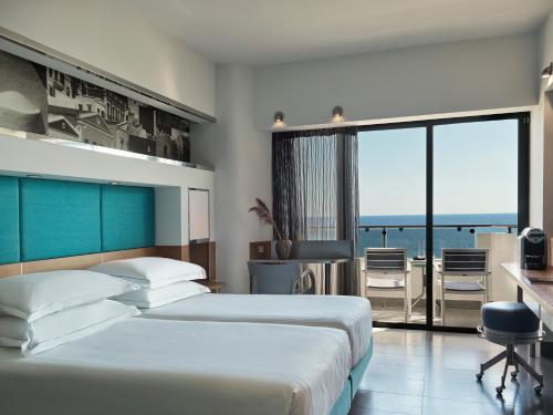 two beds in a room with a view of the ocean at Esperos Palace Resort in Faliraki