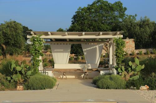 a pavilion with a picnic table in a garden at TRULLI TERRA DI MEZZO in Cisternino