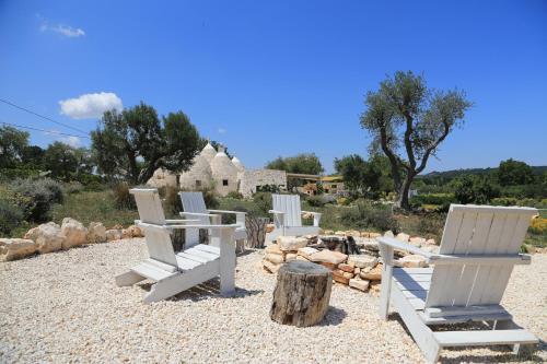 a group of white chairs sitting on a beach at TRULLI TERRA DI MEZZO in Cisternino