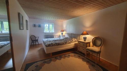 a small bedroom with a bed and a chair at Rolsø Retreat - the apartment in Knebel