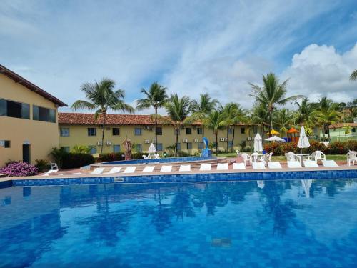 uma piscina num resort com cadeiras e guarda-sóis em LC TEMPORADAS PORTOBELLO PARK HOTEL em Porto Seguro