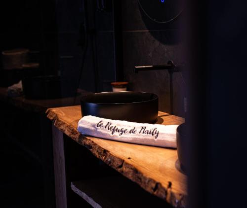 een pot bovenop een houten tafel met een boek bij Le Refuge de Maïly in Beauraing