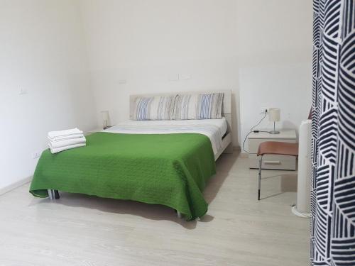 een witte slaapkamer met een groene deken op een bed bij B&B Matteotti 23 in Bologna