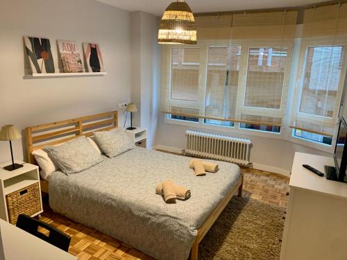 Un dormitorio con una cama con dos zapatos. en Apartamento con garaje a un paso de la playa, en Gijón