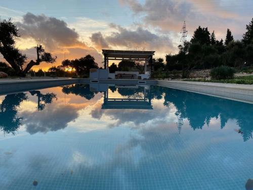 een zwembad met een zonsondergang op de achtergrond bij TRULLI TERRA DI MEZZO in Cisternino