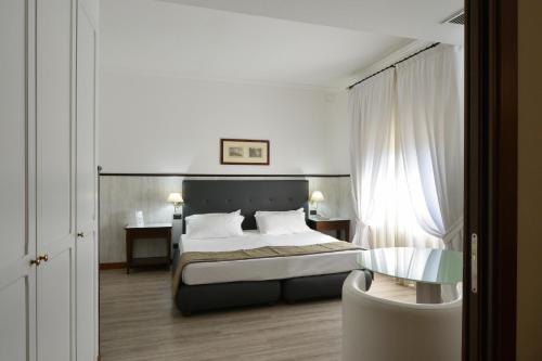 a bedroom with a bed and a chair in it at Hotel Della Valle in Agrigento