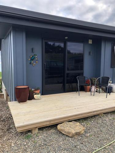 a house with a wooden deck with two chairs at ToiToi Papatotara BnB in Papatotara