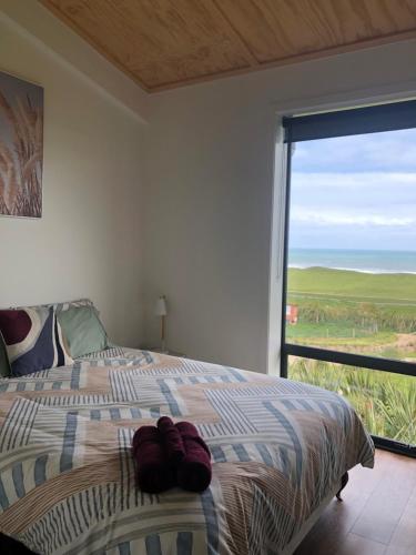 1 dormitorio con cama y ventana grande en Toi Toi Papatotara en Papatotara