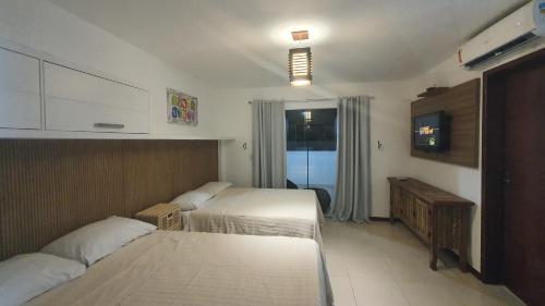 Cette chambre comprend deux lits et une télévision. dans l'établissement Aparts da Praia Grande 79, à Arraial do Cabo
